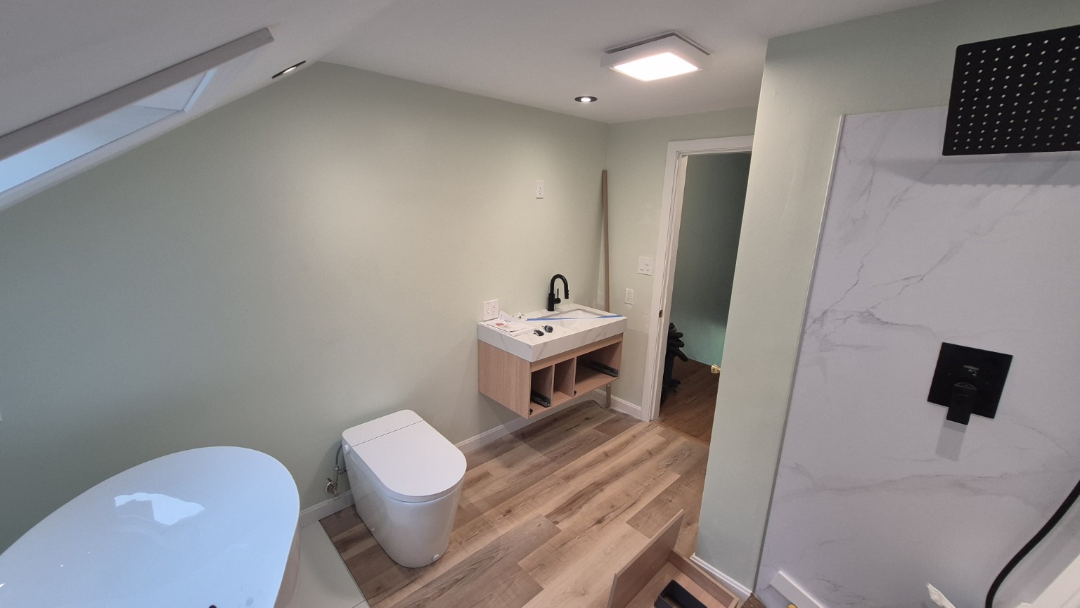 Bowdoinham bathroom with floating wood vanity, freestanding tub and black fixtures